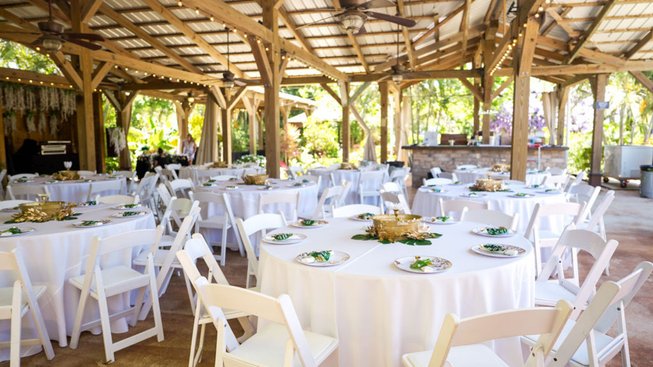 Round tables set with white linens under the pavilion